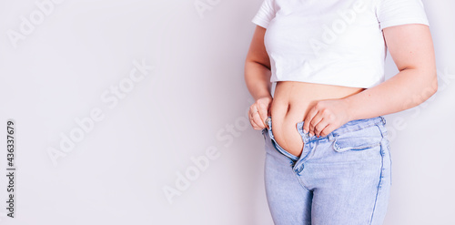 a woman dresses in jeans after giving birth. The concept of the diet-close-up of women's hands can not button their pants because of the increase in fat on the thighs after childbirth