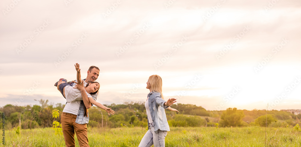 Happy family in the park evening light. The lights of a sun. Mom, dad and baby happy walk at sunset. The concept of a happy family Happy family in the park evening light. The lights of a sun. Mom, dad and baby happy walk at sunset. The concept of a happy family
