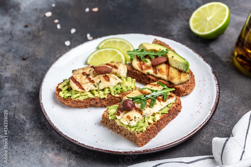 Grilled halloumi sandwich with avocado guacamole, arugula. Toast with grilled cheese and avocado. Healthy food