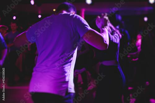 Couples dancing traditional latin argentinian dance milonga in the ballroom, tango salsa bachata kizomba lesson in the red, purple and violet lights, dance festival