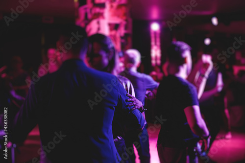 Couples dancing traditional latin argentinian dance milonga in the ballroom, tango salsa bachata kizomba lesson in the red, purple and violet lights, dance festival © tsuguliev
