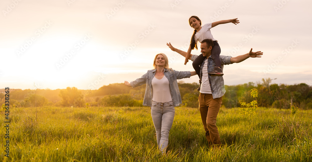 Happy family in the park evening light. The lights of a sun. Mom, dad and baby happy walk at sunset. The concept of a happy family Happy family in the park evening light. The lights of a sun. Mom, dad and baby happy walk at sunset. The concept of a happy family
