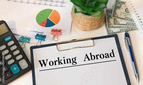 Paper with Working Abroad on the table, calculator and money