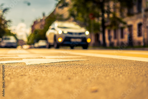 Clear day in the big city, the car goes down the street. View from the pedestrian crossing