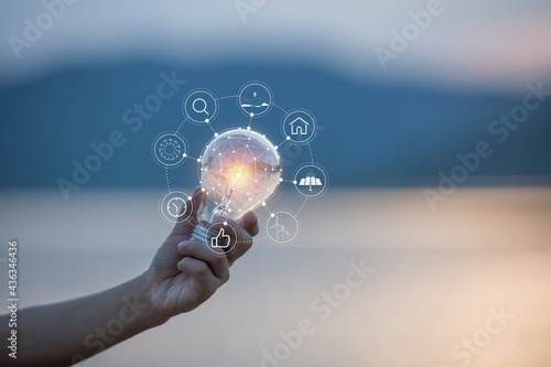 hand holding light bulb against nature, icons energy sources for renewable,