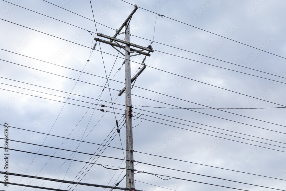 Tall wood power pole with a grid of power lines in numerous levels and directions against an overcast sky, horizontal aspect Tall wood power pole with a grid of power lines in numerous levels and directions against an overcast sky, horizontal aspect
