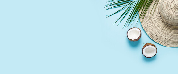 Women's hat with wide brim, sunglasses, coconut and a branch of a palm tree on a blue background. Summer concept, vacation at sea. Banner. Flat lay, top view