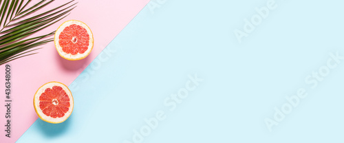 Fototapeta Naklejka Na Ścianę i Meble -  Sliced grapefruit and palm branch on a pink and blue background. Banner. Flat lay, top view