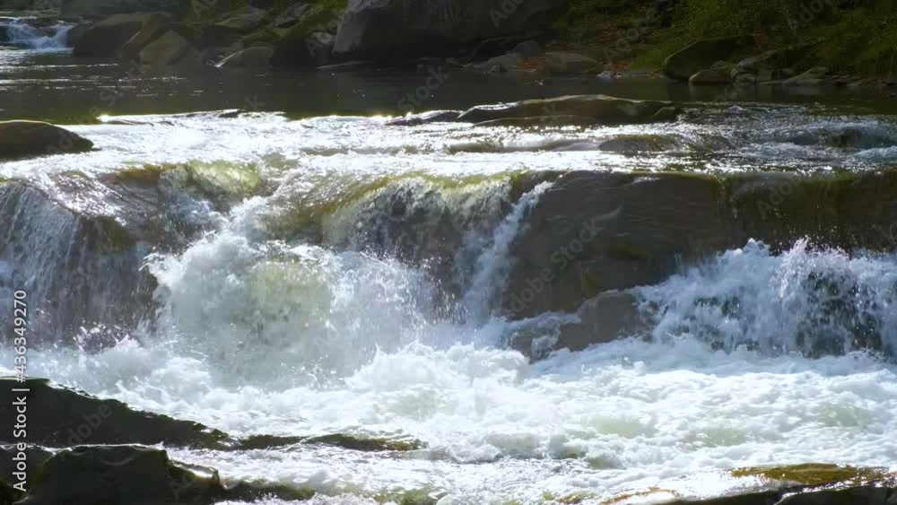 Mountain river with clear turquoise water falling down in cascades between wet boulders with thick white foam. Mountain river with clear turquoise water falling down in cascades between wet boulders with thick white foam.