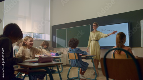 Students learning at elementary school. Female teacher standing at blackboard
