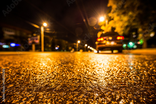 Night city after rain, parked the car at the roadside. View from a wide angle at the level of the asphalt