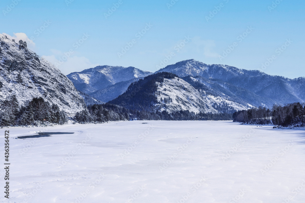 Mountains and frozen river in winter, sunny