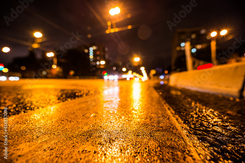 Night city after rain, the glowing lights of approaching cars. Wide angle view of the level of the pedestrian crossing