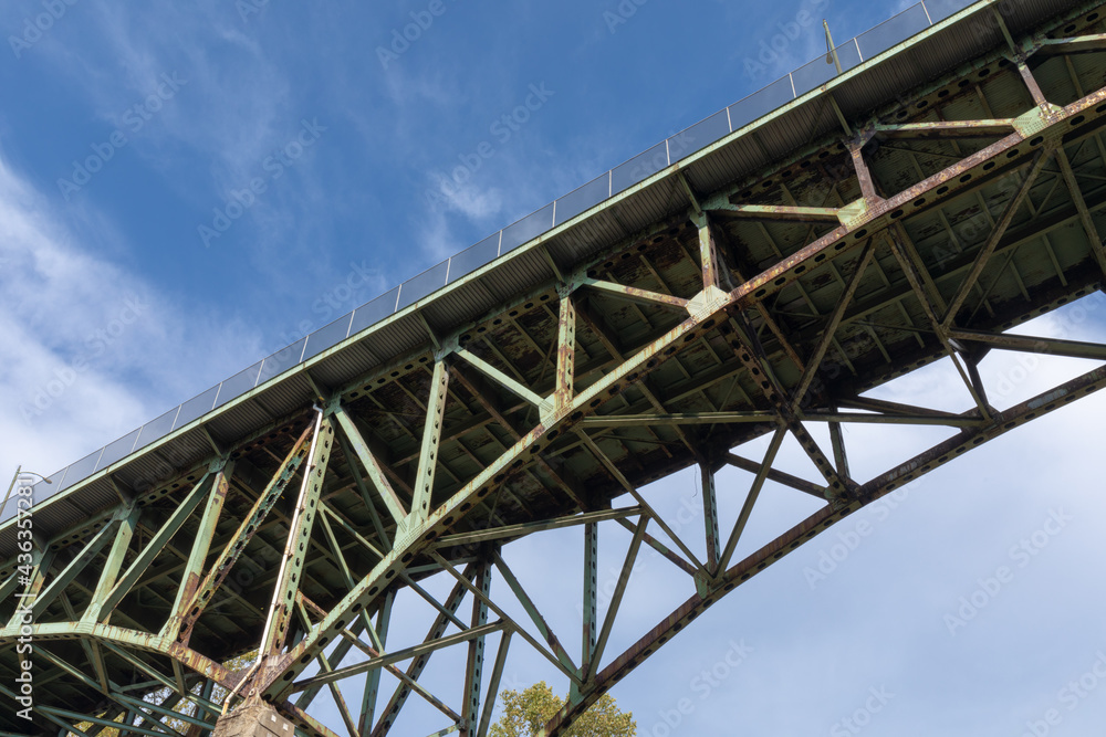 Arch bridge with pedestrian walkway seen from below, green paint with rusting metal, crumbling American infrastructure, horizontal aspect Arch bridge with pedestrian walkway seen from below, green paint with rusting metal, crumbling American infrastructure, horizontal aspect