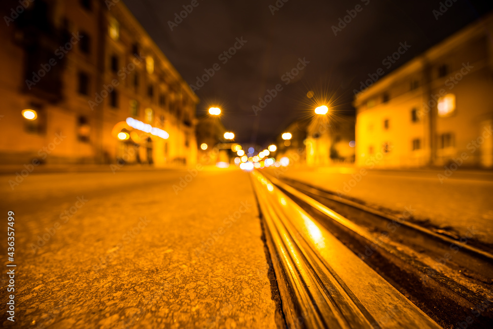 Night highway with rails, the glowing lights of approaching cars. Wide angle view of the level of the rails