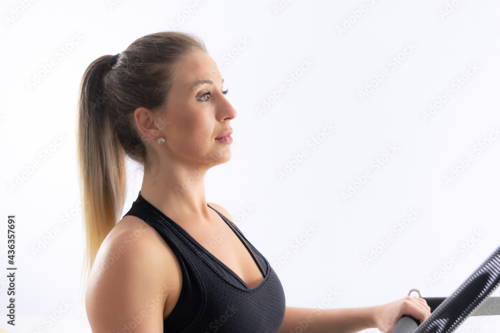 Woman doing pilates exercises in a cadillac equipment, white backgound, high key. Woman doing pilates exercises in a cadillac equipment, white backgound, high key.