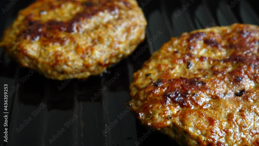 The fried cutlet for hamburger rotates on the grill pan. The fried cutlet for hamburger rotates on the grill pan.
