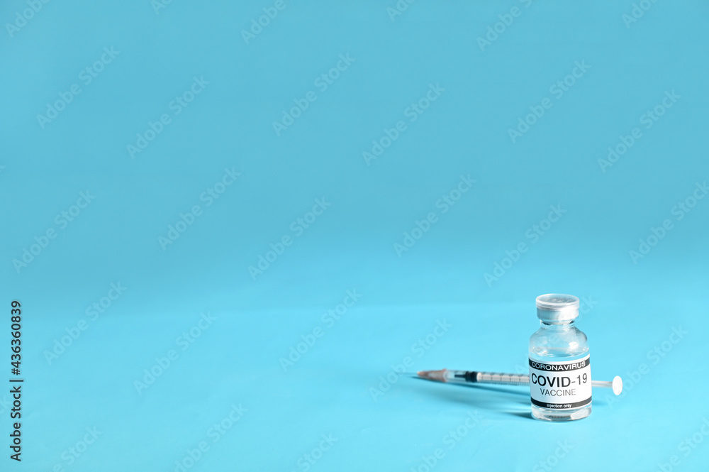 Coronavirus COVID-19 Vaccine Glass Bottle and syringe on blue surface with blue background at Thailand. Concept viruses spread throughout the world. Selective Focus. Coronavirus COVID-19 Vaccine Glass Bottle and syringe on blue surface with blue background at Thailand. Concept viruses spread throughout the world. Selective Focus.