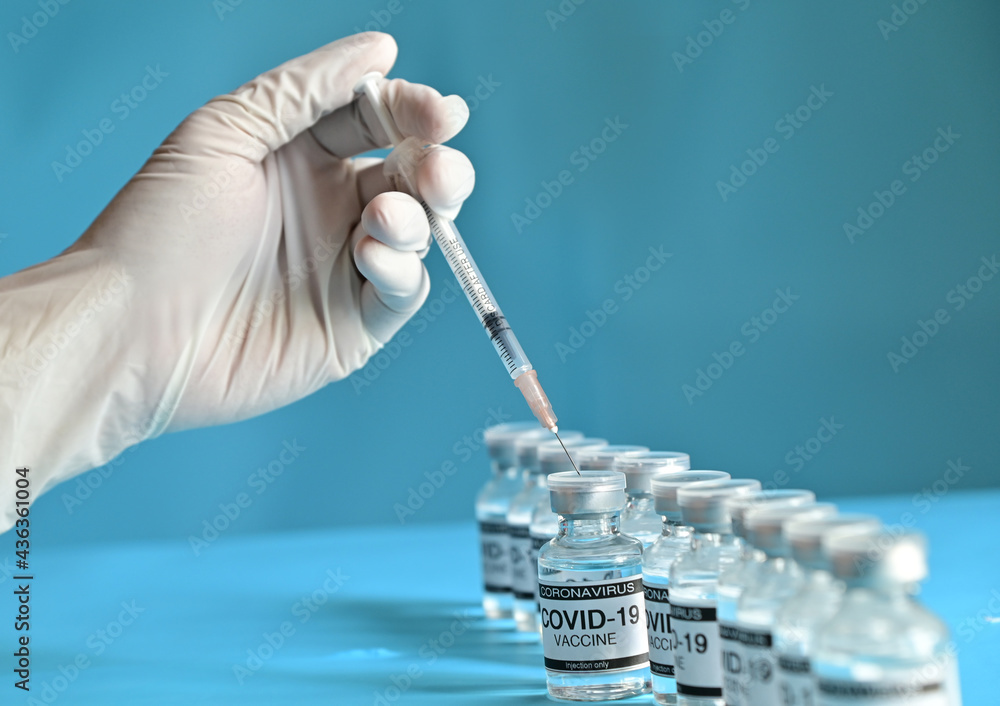 Doctor or Nurse hands holding the syringe with Coronavirus COVID-19 Vaccine Glass Bottle on blue surface with blue background at Thailand. Concept viruses spread throughout the world. Selective Focus. Doctor or Nurse hands holding the syringe with Coronavirus COVID-19 Vaccine Glass Bottle on blue surface with blue background at Thailand. Concept viruses spread throughout the world. Selective Focus.