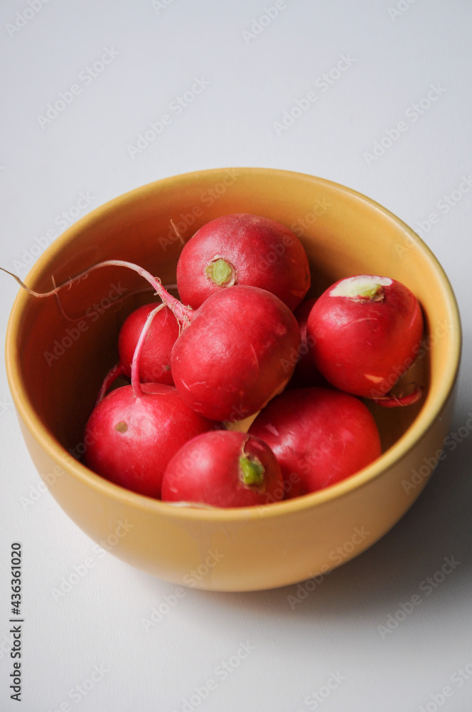 Fresh radish in a yellow bowl on a white background Fresh radish in a yellow bowl on a white background