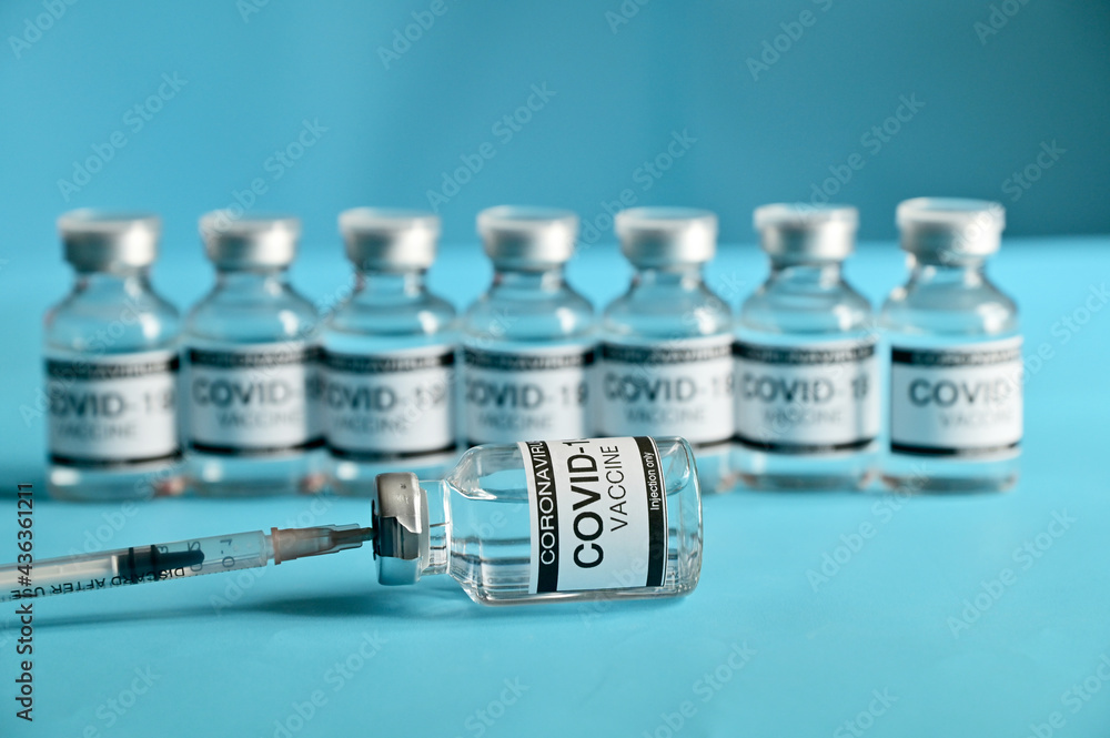 Coronavirus COVID-19 Vaccine Glass Bottle and syringe on blue surface with blue background at Thailand. Concept viruses spread throughout the world. Selective Focus. Coronavirus COVID-19 Vaccine Glass Bottle and syringe on blue surface with blue background at Thailand. Concept viruses spread throughout the world. Selective Focus.