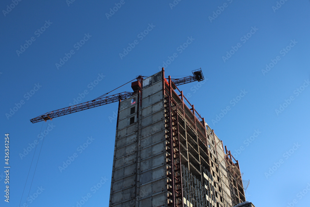 Fototapeta premium building frame skyscraper on a construction site with a crane in the sky