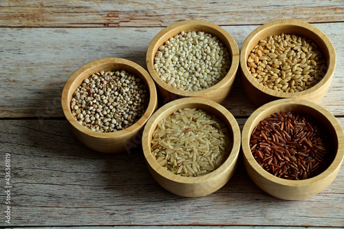 Brown Glutinious Rice  Red Jasmine Rice  Oat Rice  Barley  Millet Rice  Brown Wheat in wooden bowl on wooden table background.