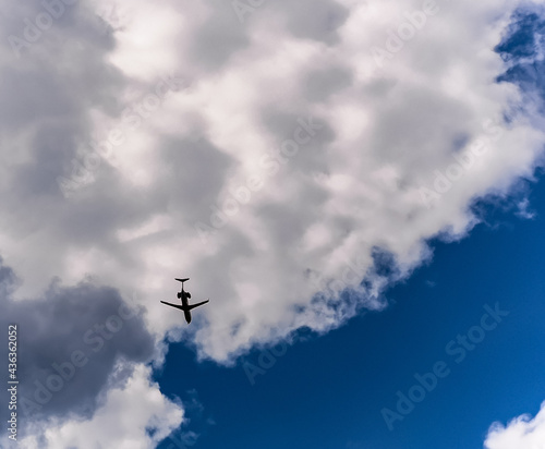 Silhouette of aeroplane over clouds and blue sky