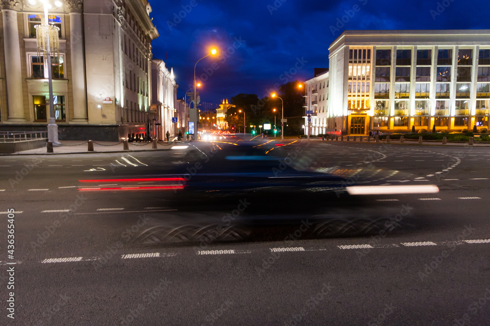 The motion of a blurred car along the avenue in the evening.