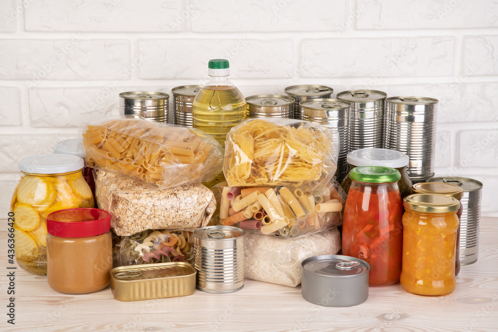 Food donations such as pasta, rice, oil, peanut butter, canned food, jam and other on white table Food donations such as pasta, rice, oil, peanut butter, canned food, jam and other on white table