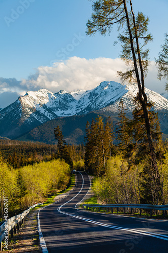 Beautiful view of the snow-capped peaks of the Tatra Mountains. The road leading towards the mountains. Afternoon warm sun. Poland.