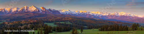 A beautiful panorama of the entire range of the Tatra Mountains. The colorful rays of the sun illuminate the snow-covered, white mountains. The view at sunrise. Poland
