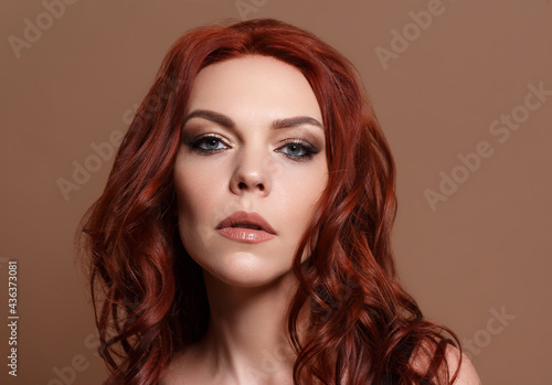 Red-haired beautiful woman on a beige background.