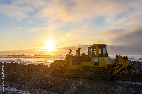 Yellow tractor in winter tundra. The road construction. Bulldozer.