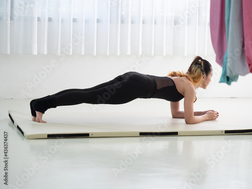 Young beautiful Asian dancer dressed in black color warming up and stretching before aerial dance at the studio.