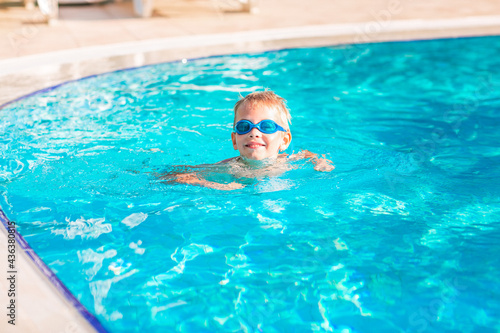 Cute happy little boy in goggles swimming and snorking in the swimming pool