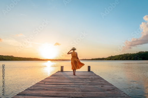 Woman walking along the pier at sunset
