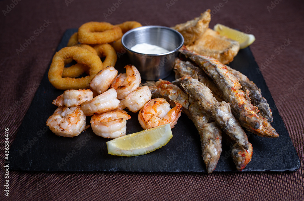 snacks to beer on a black plate of fish and onion rings. snacks to beer on a black plate of fish and onion rings.
