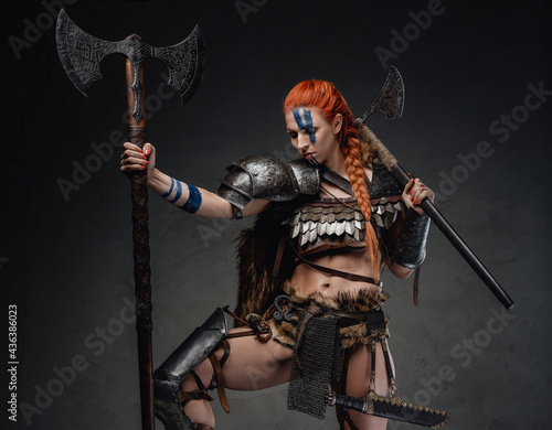 Muscular woman warrior from north with two axes in dark background