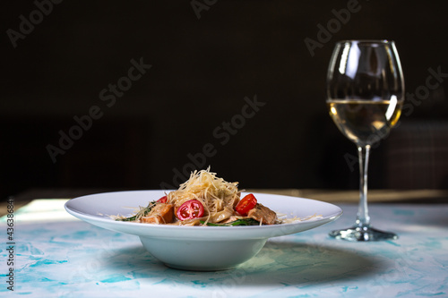 Pasta with hard cheese and meat with wine in the background.