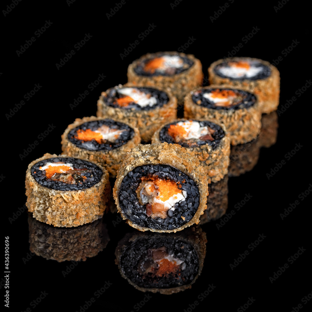 Japanese Hot Sushi Roll in tempura isolated on black background. Asian Roll pieces with black rice, salmon, avocado Japanese Hot Sushi Roll in tempura isolated on black background. Asian Roll pieces with black rice, salmon, avocado