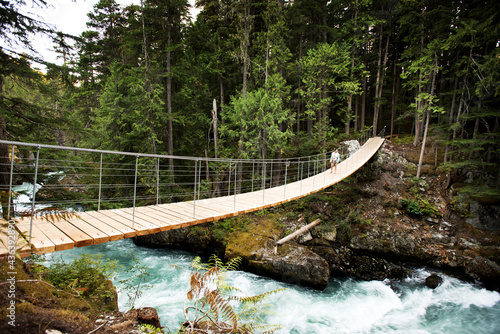 A woman crosses a suspension foot bridge over the Cheakamus River on the train wreck trail. photo