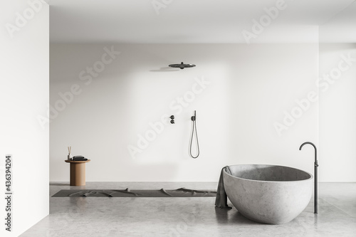 Light bathroom interior with shower and bathtub on concrete floor