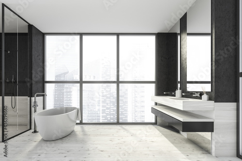 Modern design bathroom interior with shower cabin, white oval bathtub, double sink countertop, silver faucets. Panoramic window with skyscrapers city view. Wood and concrete materials.