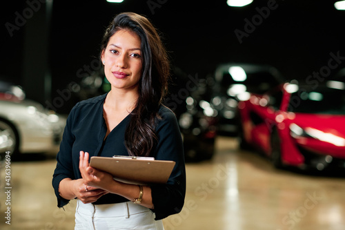 young latin saleswoman selling luxury cars photo