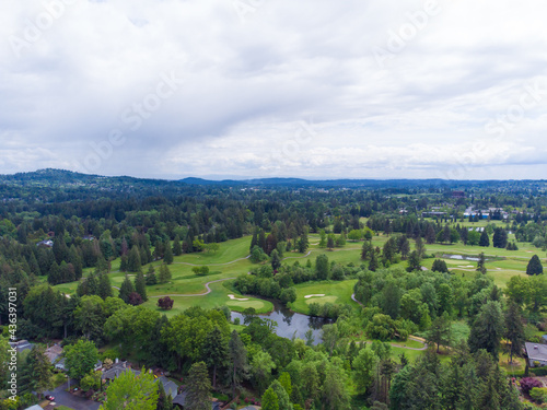 In the photo we see a beautiful nature - woodland  lake. Mountains can be seen in the distance. There are white clouds in the blue sky. View from above. Shooting from a drone.