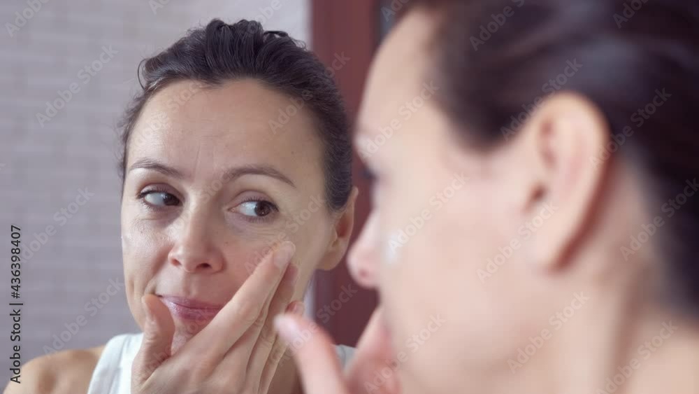 Anti aging cream. A nice woman use an anti-aging lotion against face wrinkles by the mirror. Anti aging cream. A nice woman use an anti-aging lotion against face wrinkles by the mirror.