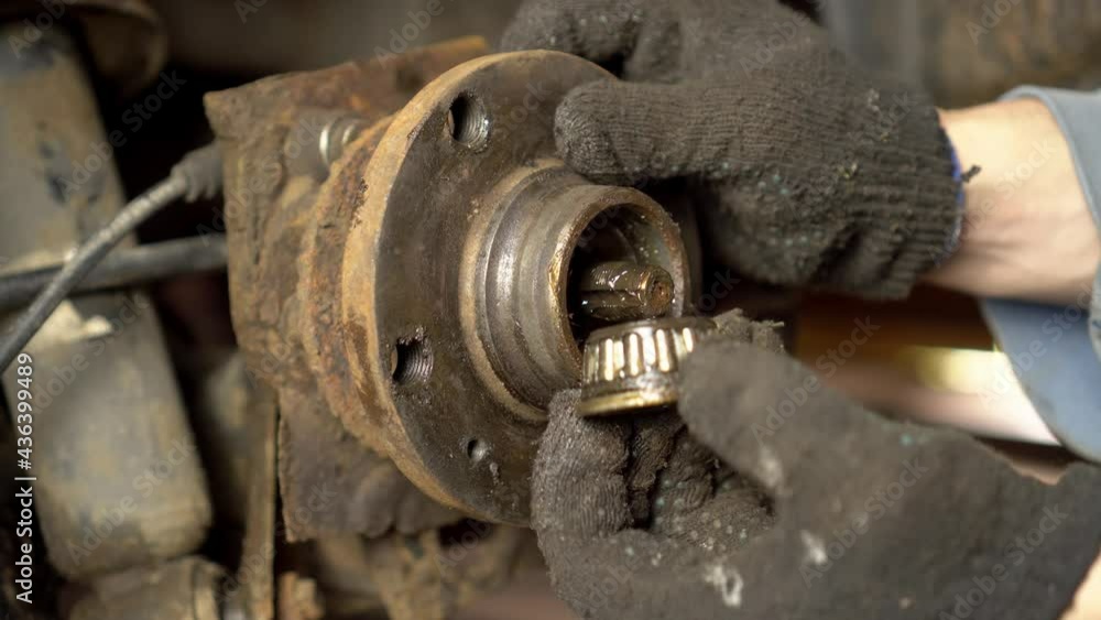 The hands of a master or auto mechanic repair the hub and bearing in the car. It removes the hub to replace the roller bearing. Inspection of the car suspension. The hands of a master or auto mechanic repair the hub and bearing in the car. It removes the hub to replace the roller bearing. Inspection of the car suspension.