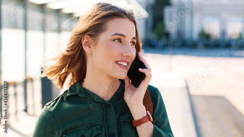 Close up portrait of smiling joyful young Caucasian beautiful female tourist standing on street in city near airport calling on smartphone in good mood. Traveling  vacation  post-quarantine concept