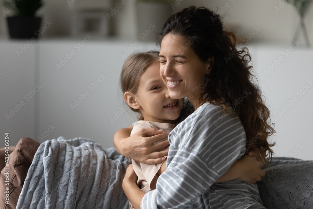 Smiling young Latino mother hug cuddle small biracial daughter show love care. Happy Hispanic mom embrace little ethnic girl child, relax enjoy family weekend at home together. Motherhood concept.